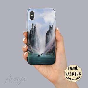 May include: A smartphone case featuring a detailed illustration of two towering stone statues standing on opposite sides of a river, with small boats floating on the water below under a cloudy sky, rendered in shades of blue, gray, and white.