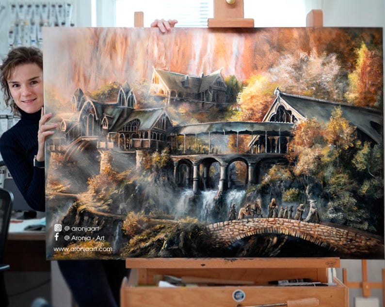 Op de afbeelding: Een groot rechthoekig olieverfschilderij met een fantasielandschap met complexe stenen gebouwen, een brug met meerdere bogen en een waterval. Een groep kleine figuren loopt over een stenen brug. Tekst luidt @aronjaart.