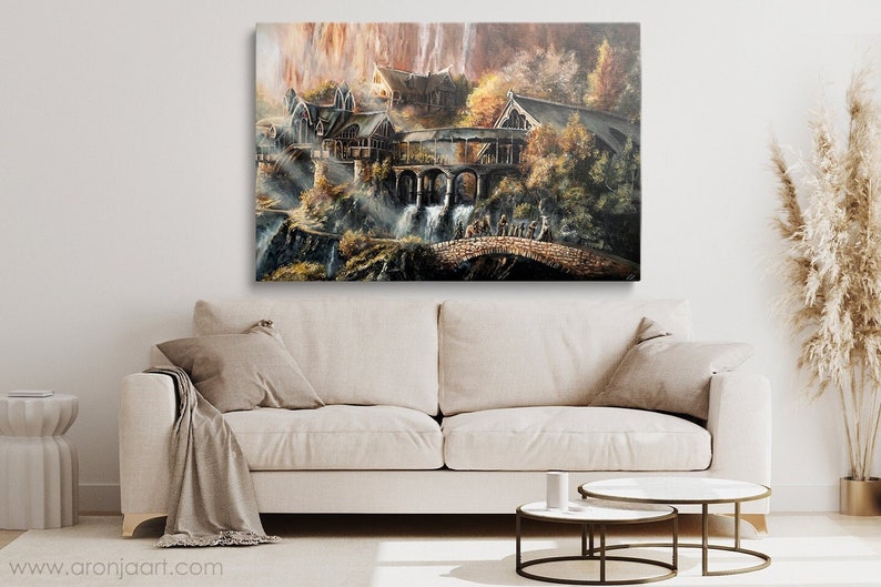 Op de afbeelding: Een rechthoekige canvas print met een fantasielandschap met stenen gebouwen, boogbruggen en watervallen. De sc&egrave;ne bevat warme herfsttinten, gouden licht en een groep figuren die over een stenen brug lopen.