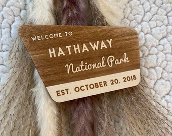 May include: Wooden sign with the text "Welcome to Hathaway National Park Est. October 20, 2018". The sign is brown with white lettering and has a wood grain texture.