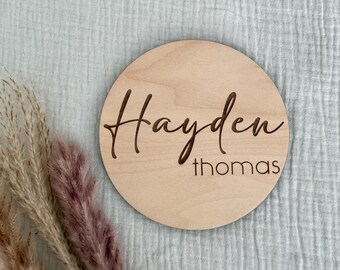 May include: A round wooden plaque with the name "Hayden Thomas" engraved in a cursive font.