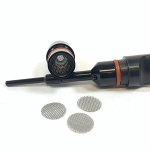 Puede incluir: Un vaporizador negro con un filtro de malla y tres pequeñas pantallas de malla redondas. El vaporizador tiene un anillo rojo cerca de la parte superior, sobre un fondo blanco.