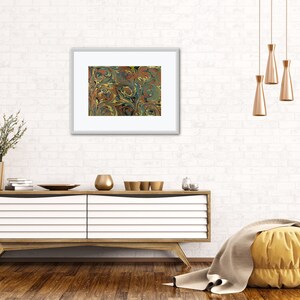 May include: A framed print of a marbled design with swirls of blue, green, yellow, and brown. The print is hanging on a white brick wall above a white dresser with a wooden top.