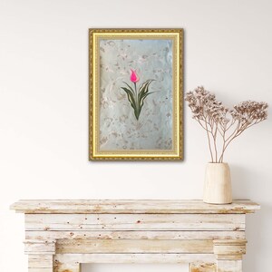 May include: A framed artwork featuring a pink tulip with green leaves on a light blue background with a marbled pattern. The frame is gold.