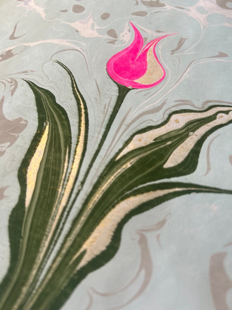 May include: A pink tulip with gold accents on a marbled background with green and gold swirls.