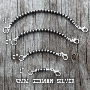 May include: Four beaded silver chain straps, 1 to 4 inches long, with lobster claw clasps and split rings. The chains are made of 4mm German silver beads. The image is on a weathered wood background.