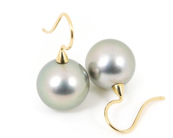 May include: A pair of silver pearl earrings with gold hooks. The pearls are round and have a slight iridescent sheen.