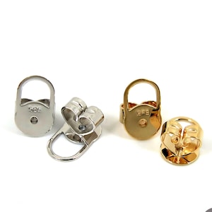 Pode incluir: Quatro fechos de brincos em tons de prata e ouro são exibidos em um fundo branco. Dois são prateados e dois dourados. Cada fecho tem uma argola e um pequeno orifício. Os fechos são provavelmente para brincos de pressão.