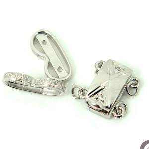 May include: Silver tone clasp with a decorative design and small clear stones. The clasp is designed to be used for necklaces or bracelets.