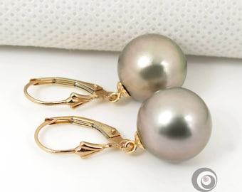 May include: A pair of gold hoop earrings with large, round, gray pearls hanging from them.