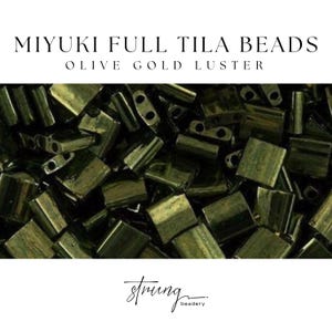 May include: Close-up of olive gold luster Miyuki Full Tila beads. The beads are rectangular with two holes, and are a dark olive green color. The text "MIYUKI FULL TILA BEADS OLIVE GOLD LUSTER" is at the top of the image. The "strung beadery" logo is at the bottom.