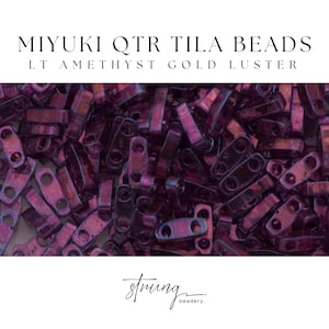 May include: Close-up of Miyuki QTR Tila beads in a light amethyst gold luster. The beads are rectangular with two holes and a metallic sheen. The image includes the text "MIYUKI QTR TILA BEADS" and "LT AMETHYST GOLD LUSTER". The "strung beadery" logo is also visible.