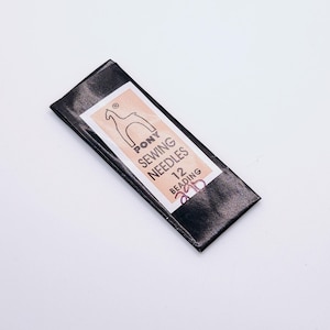 May include: A package of Pony sewing needles for beading. The label is white and peach with black text and a horse logo. The package is black.