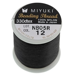 May include: A spool of black Miyuki beading thread made of 100% nylon. The white label on top displays the text Miyuki Beading Thread, 330dtex, 100% Nylon, Made in Japan, Lot NB05R, and Col. 12, along with the company name and phone number.