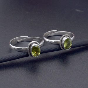 Peut inclure: Deux anneaux de pied en argent avec des pierres précieuses ovales vertes. Les anneaux sont réglables et ont un design simple.