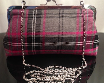 May include: A pink, gray, and black plaid clutch purse with a silver chain strap.