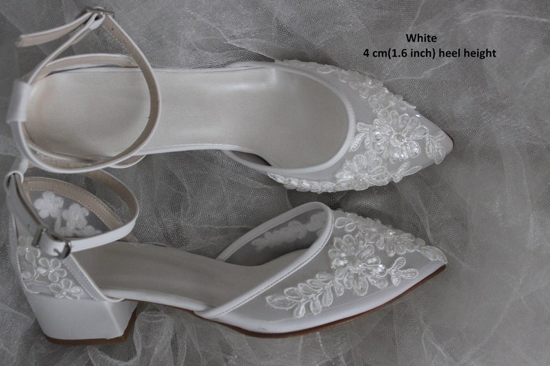 May include: White bridal shoes with a 4 cm (1.6 inch) heel height. The shoes are made of satin and have a delicate lace design with sequins.
