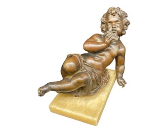 19th century bronze sculpture of a putto, cherub, or cupid playing a pan flute, with a medal-like patina and onyx base, France.