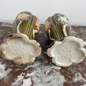 May include: Two green ceramic vases with floral designs and white bases. The bases are marked with the number "1359".