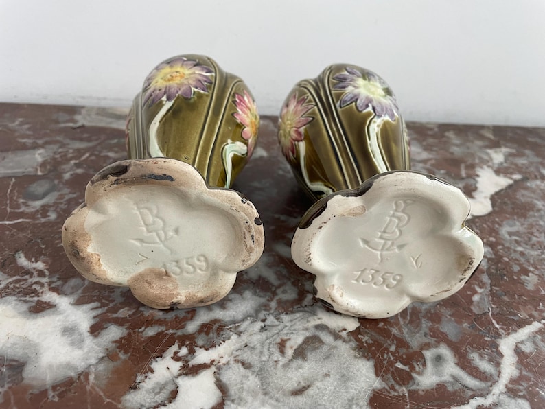 May include: Two green ceramic vases with floral designs and white bases. The bases are marked with the number "1359".