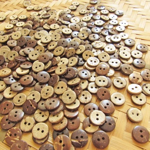 May include: A large pile of brown and natural coconut shell buttons. The buttons are arranged on a woven bamboo surface.