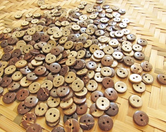 May include: A large pile of brown and natural coconut shell buttons. The buttons are arranged on a woven bamboo surface.