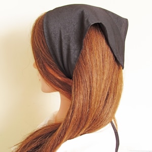 May include: A black bandana tied around a person's head, covering part of their hair.