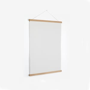 May include: A wooden poster hanger with a white canvas hanging from it. The hanger has a simple design and is made of natural wood.