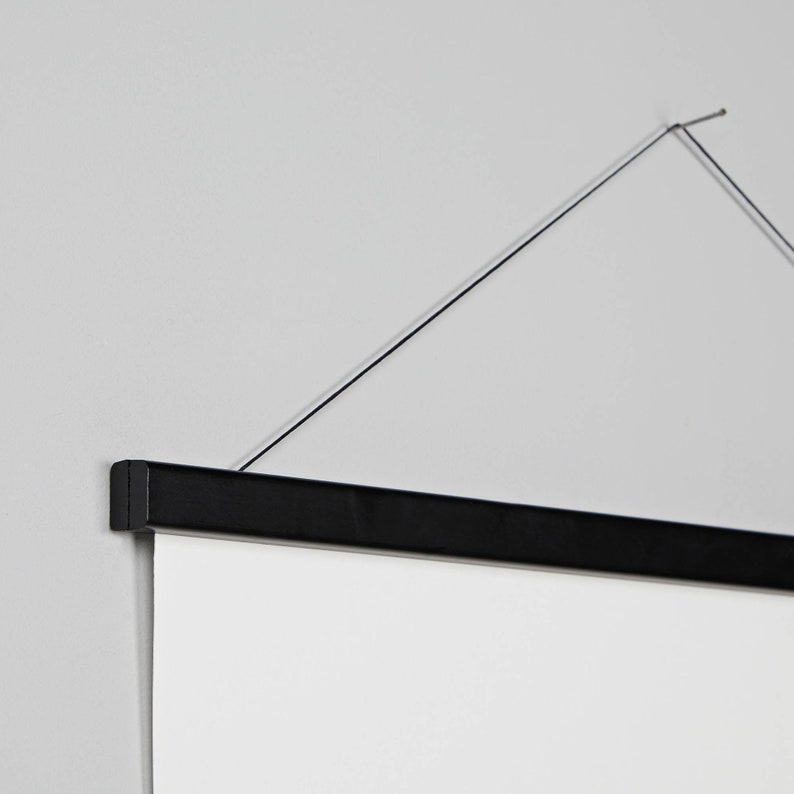 May include: A black hanging frame with a white canvas insert. The frame has a thin black cord attached to the top for hanging.