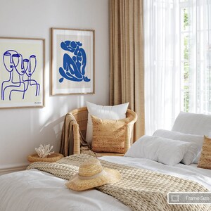 a bedroom with a white bed and two pictures on the wall
