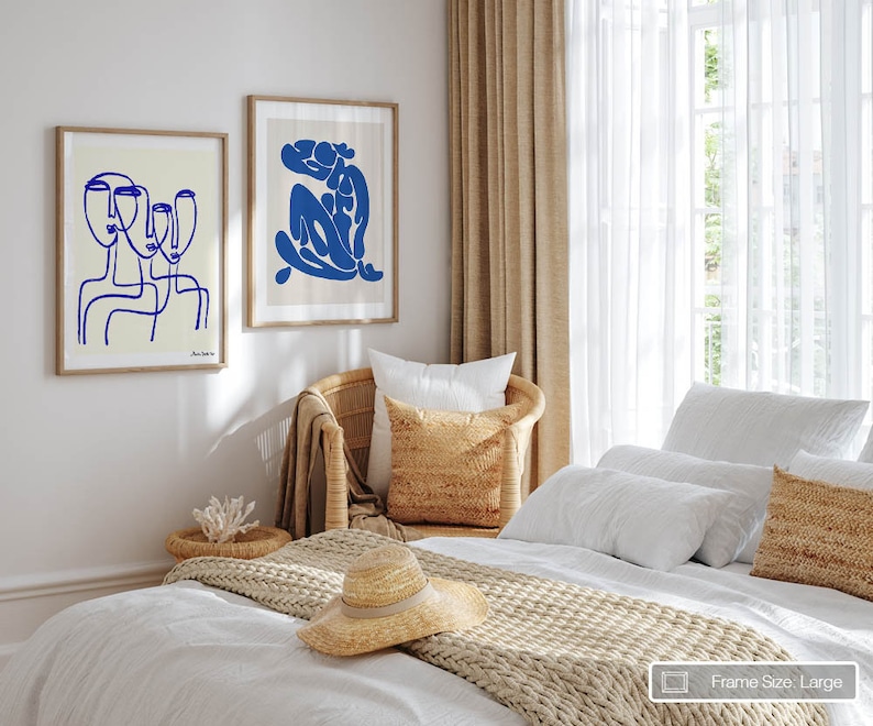 a bedroom with a white bed and two pictures on the wall