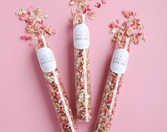 Può includere: Tre tubi di vetro trasparente riempiti di petali di fiori rosa e bianchi. Ogni tubo ha un'etichetta bianca con il testo "Sprinkled with Love" in corsivo nero.
