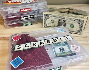 May include: A clear plastic storage box with a red hessian bag inside. The box contains Scrabble tiles and score cards. The box has a label that says "Scrabble - A Savings Game".