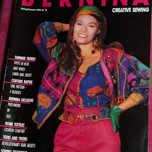 Puede incluir: Una portada de revista con una mujer que lleva una chaqueta estampada de colores y una falda rosa. La revista se titula "BERNINA CREATIVE SEWING" y el número es Primavera/Verano 1992, Nr. 18. La portada de la revista también incluye texto sobre las tendencias de verano, la costura rápida y el patchwork exclusivo de Bernina.