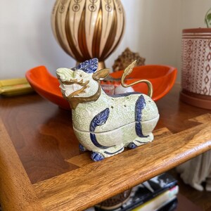 May include: A ceramic incense burner shaped like a mythical creature with green, white, and blue details. The burner has a gold-colored horn and a tail.