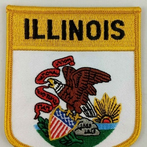 May include: An embroidered patch featuring the state seal of Illinois. The patch is yellow with a white center and features a bald eagle, a shield with red and white stripes, a sun, and a scroll with the words "State of Illinois" in red.