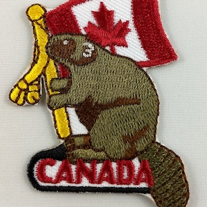 May include: Embroidered patch depicting a beaver holding a Canadian flag. The flag is red and white with a maple leaf. The beaver is brown and tan, and the word "CANADA" is at the bottom in red letters.