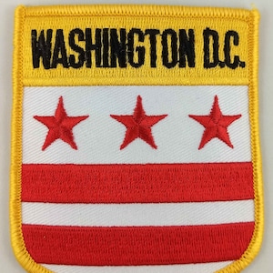 May include: An embroidered patch in yellow and gold with the text "WASHINGTON D.C." and three red stars above three red and white stripes.