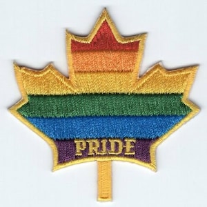 Può includere: Una toppa a forma di foglia d'acero canadese con i colori dell'arcobaleno e la parola "PRIDE" ricamata in viola nella parte inferiore.