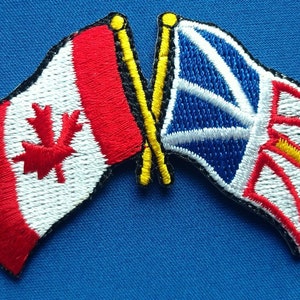 Può includere: Una bandiera canadese rossa e bianca e una bandiera britannica blu e bianca si incrociano. Le bandiere sono ricamate e hanno pali gialli.