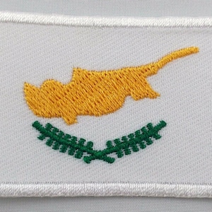 May include: White embroidered patch with the yellow outline of the island of Cyprus and a green olive branch wreath below.