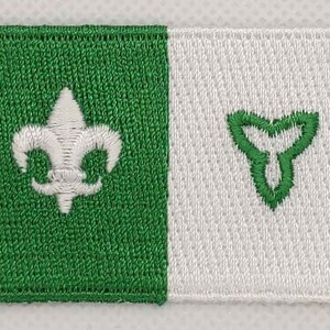 May include: A green and white embroidered patch with a white fleur-de-lis on the left side and a green trillium on the right side.
