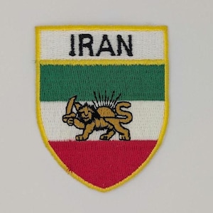 May include: Embroidered patch featuring the word "IRAN" at the top. The patch has a shield shape with a yellow border. The design includes green, white, and red stripes, and a golden lion holding a sword.