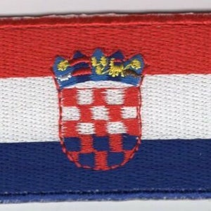May include: An embroidered patch in red, white and blue, featuring the Croatian coat of arms. The coat of arms is a shield with a chequered pattern in red and white, topped with a crown.
