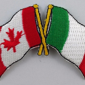 May include: A red and white Canadian flag and a green, white and red Italian flag are crossed over each other. The flags are embroidered and have a stitched border.