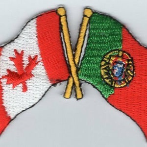 May include: Two flags crossed, the Canadian flag with a red maple leaf on a white background and a red and white stripe, and the Portuguese flag with a green and red field and the Portuguese coat of arms in the center.