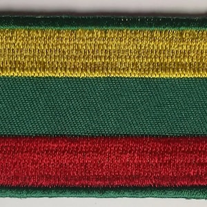 May include: Embroidered patch featuring the flag of Lithuania. The rectangular patch has horizontal stripes of yellow, green, and red, with a green border. The colors are vibrant and the stitching is detailed.