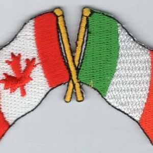 May include: Two embroidered flags crossed over each other. The flag on the left is the Canadian flag with a red maple leaf on a white background with red stripes on the top and bottom. The flag on the right is the Italian flag with green, white, and red stripes.