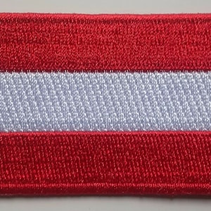 May include: An embroidered patch featuring the Austrian flag, with red, white and red stripes.