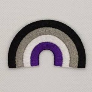 May include: Embroidered rainbow patch featuring the asexual pride flag colors: black, gray, white, purple. The patch is in the shape of an arch and is made of stitched fabric. The background is a white, textured surface.